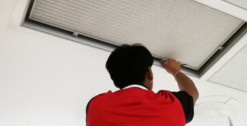 Technician installing Needlepoint Bipolar Ionization technology in ceiling